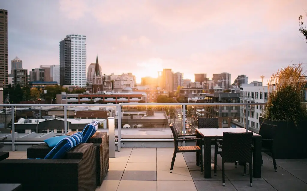 Rooftop terrace with comfortable seating and city views at sunset.