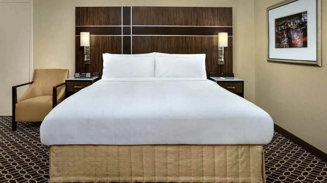 Comfortable hotel bed with crisp white linens and a view of the city.