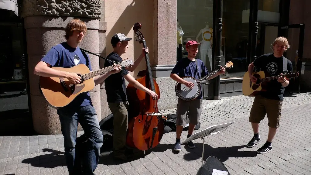 A street musician playing a guitar on a busy sidewalk.
